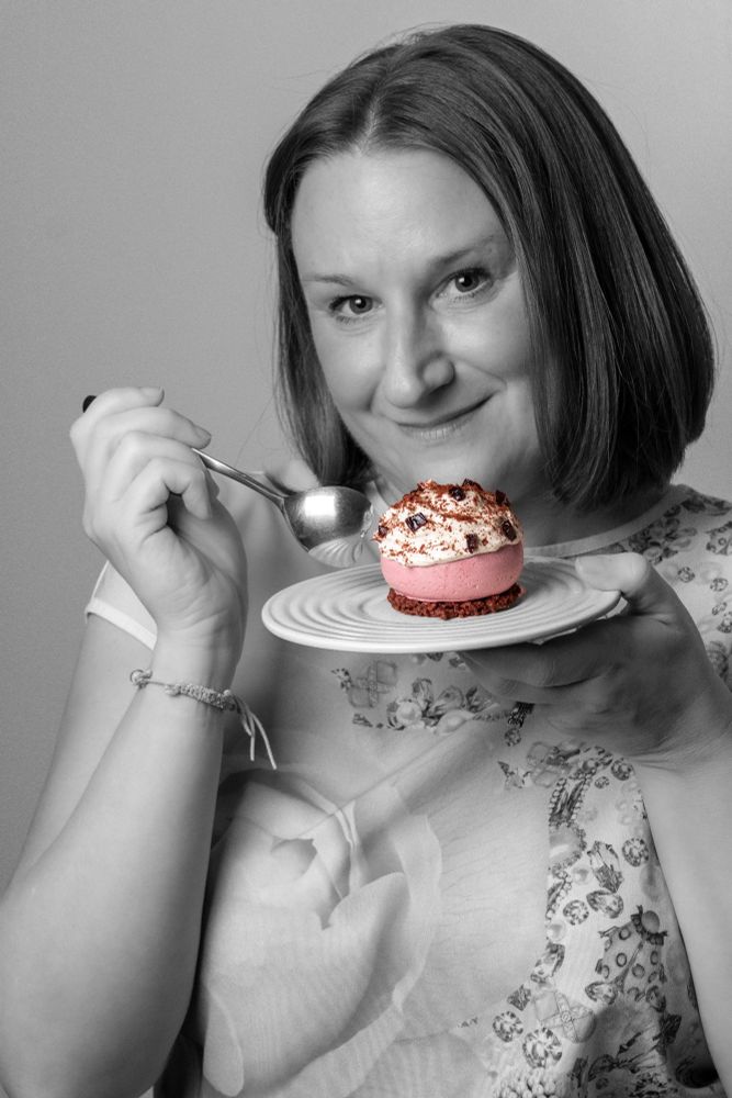 Woman in black and white eating a colourful pink vegan cake 