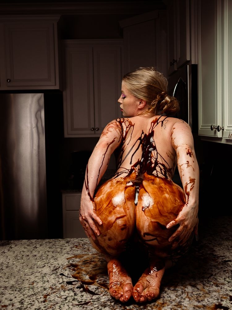 Model sitting on a kitchen counter covered in chocolate