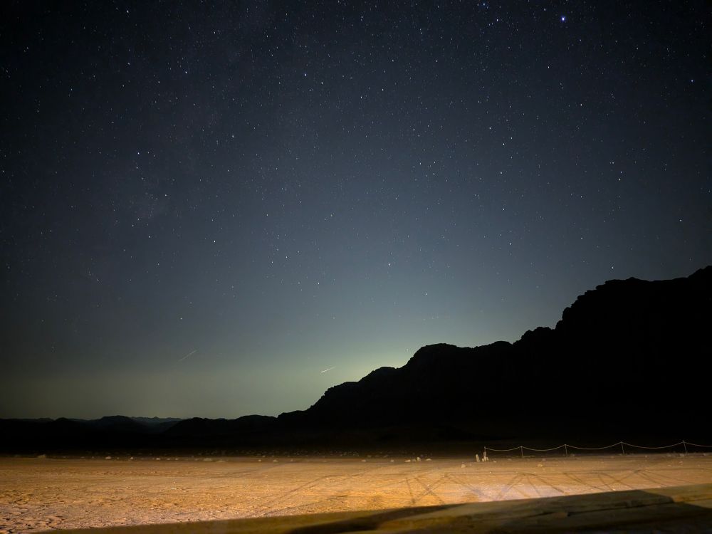 The night sky above the desert. Shooting stars cross the panoramic view.