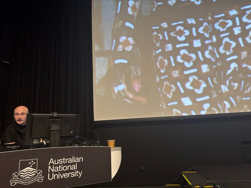 A presenter next to a big screen displaying their slides
