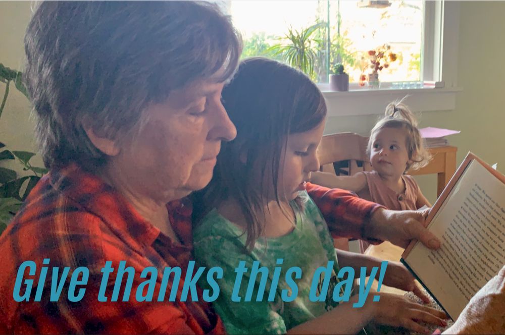 Grandmother reading a book to two of her granddaughters. Headline="Give thanks this day!"