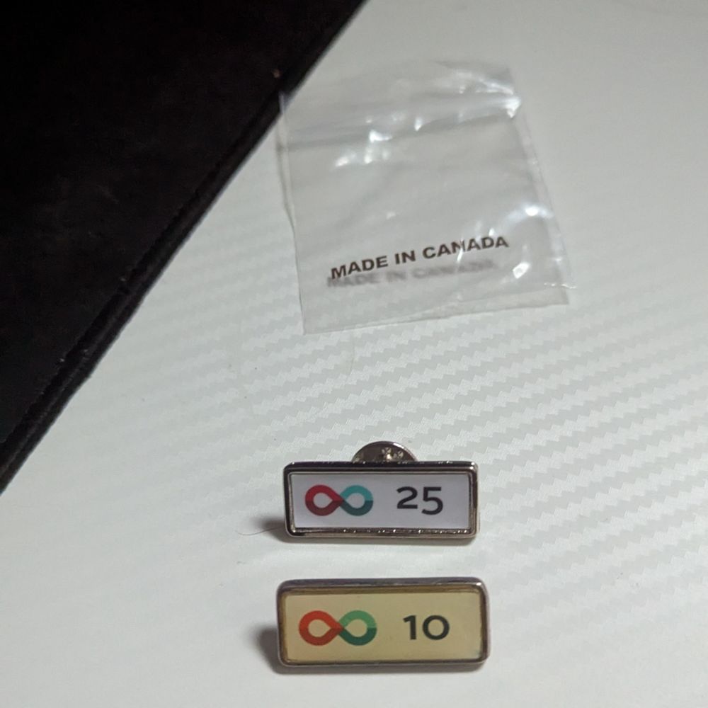 Photo showing a faded 10th donation recognition pin beside a new 25th donation recognition pin.