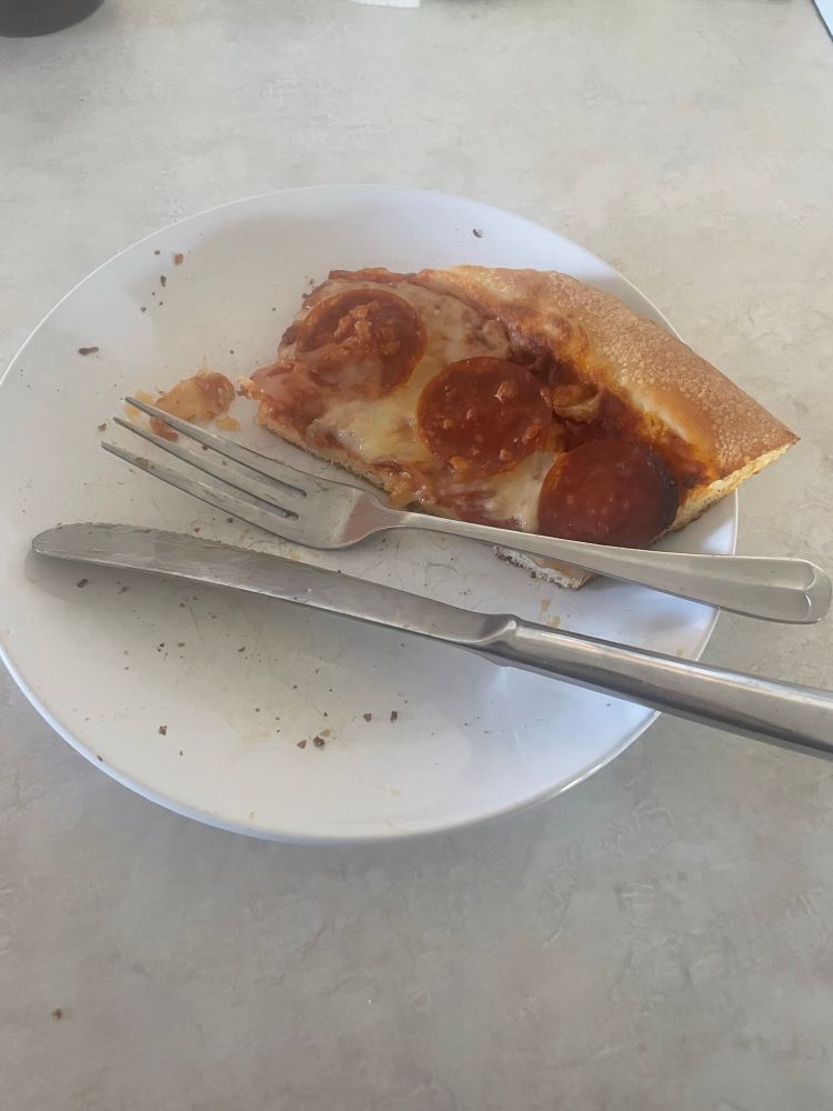 A pizza on a plate with a fork and knife. the pizza has clean cuts, indicating that the fork and knife were used.