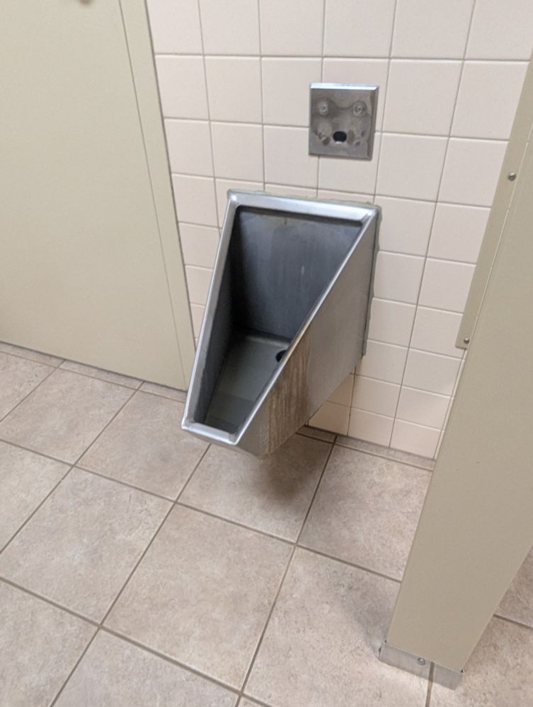 a very boxy looking urinal made of stainless steel