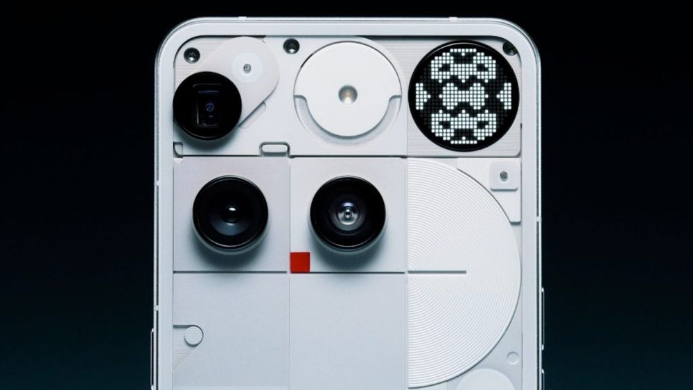 Close-up angled view of the Nothing Phone 3's transparent back panel showing a camera module with multiple black circular lenses, internal components, and a prominent dotted matrix glyph light display in the upper right corner showing a pixelated pattern