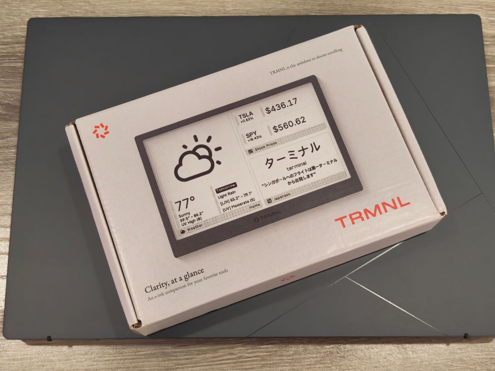 A product box containing a "TRMNL", showcases an e-ink dashboard displaying weather, stock prices, and the word "terminal" in English and Japanese
