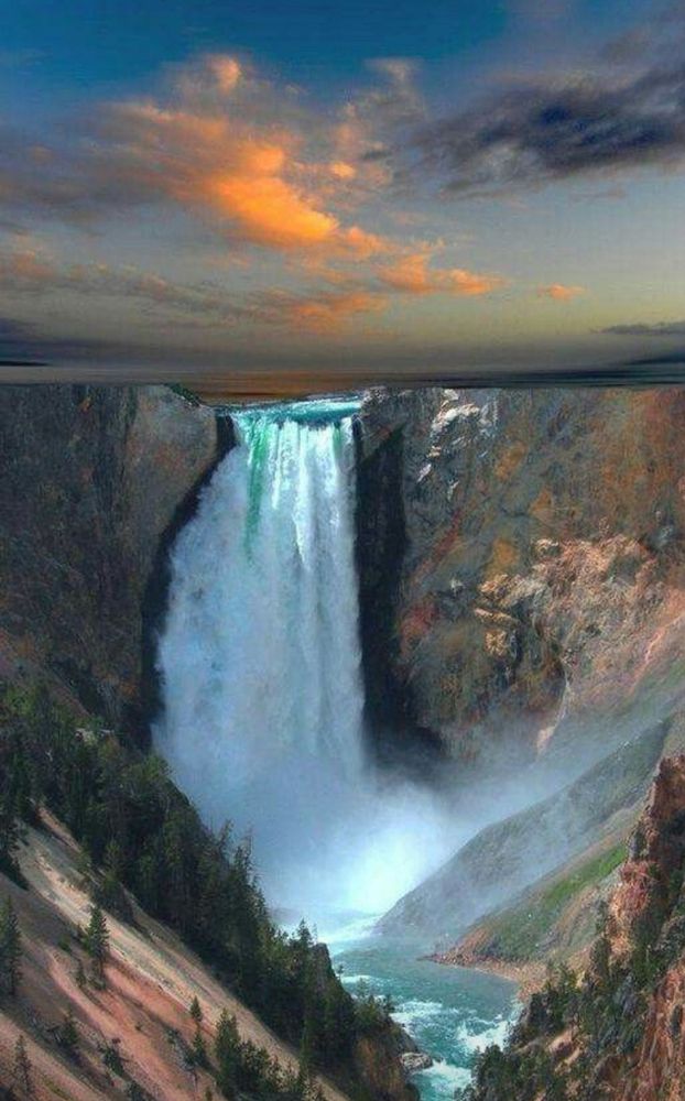 A sunlit blue clouded sky is the backdrop for an incredible cyan waterfall, as it forcefully drops into the canyon pool below.