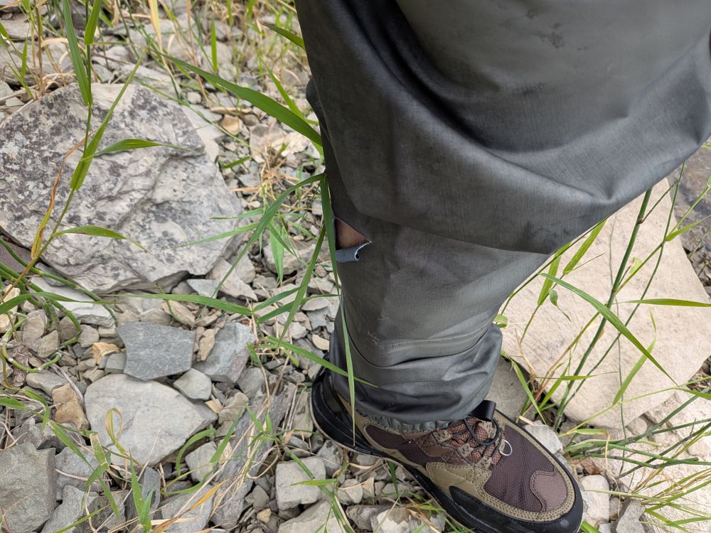 My leg in a set of boots and waders, with a gash on the back side of the knee, perfect for letting water in and counter to the purpose of waders.