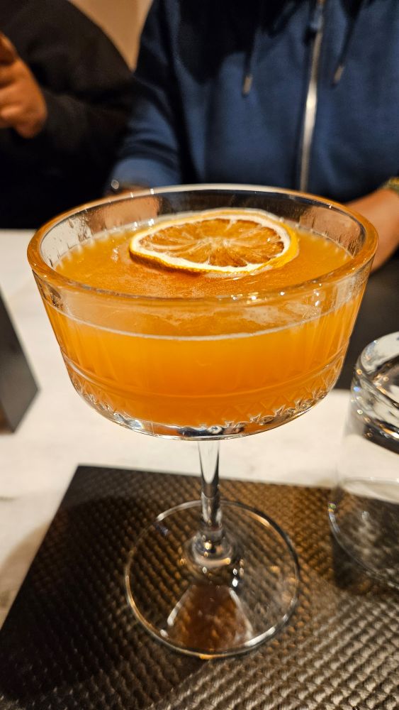 Picture of an orange cocktail with a slice of orange. 