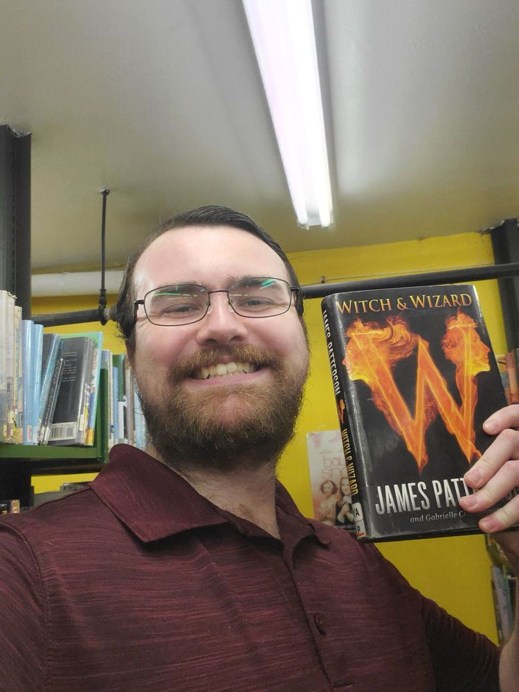 A man with a beard, smiling and holding a book