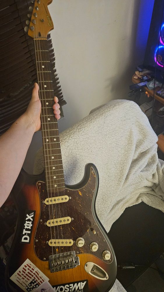 a squier stratocaster with a sunburst paint and a few assorted stickers