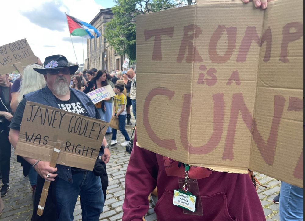 One protestor holds sign saying “Trump is a cunt” (for which comedian Janey Godley was famous). Another holds one saying “Janey Godley was right”!