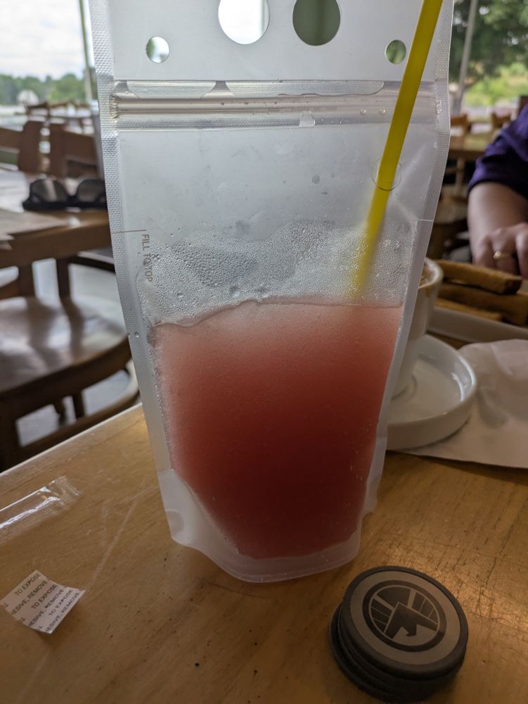 A big packet with red juice on a wooden table.