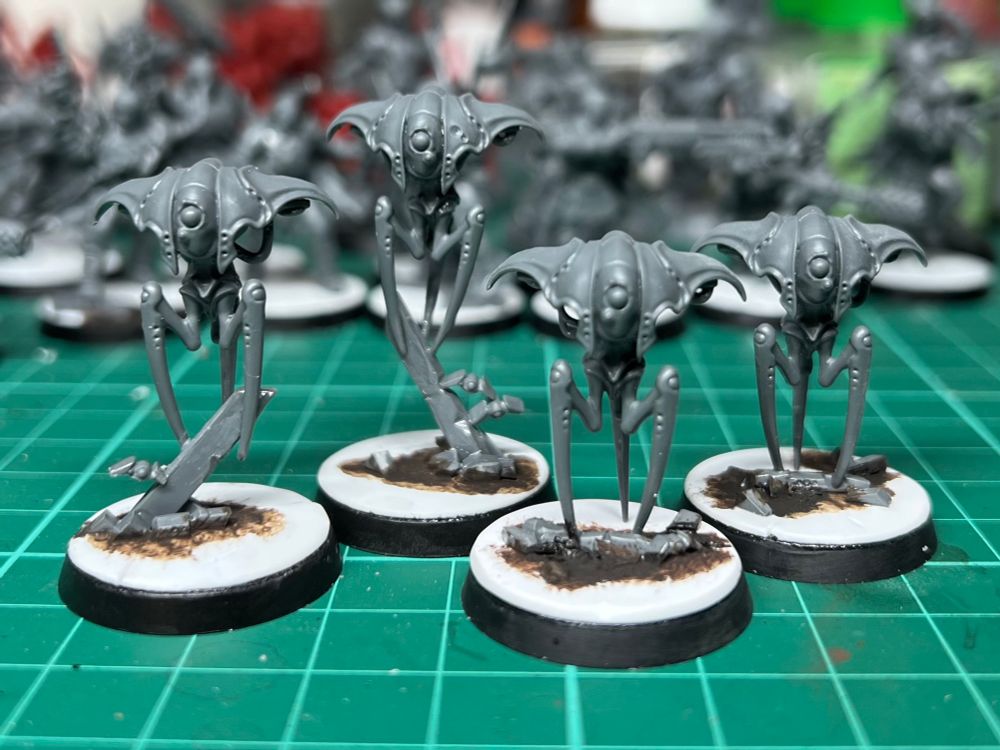 Four unpainted, grey plastic Spindle Drone miniatures from the Blackstone Fortress game 