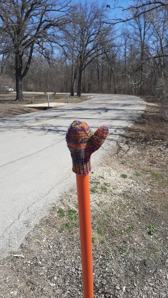 A picture of a child's mitten sitting on the end of a long orange tube