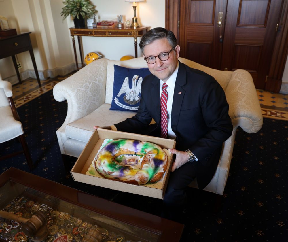 Sniveling booger-eater Mike Johnson holds a King's cake.