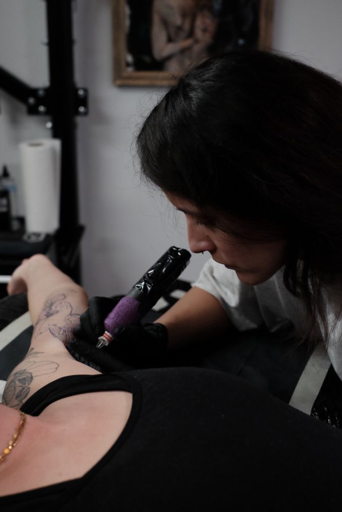 Tattoo Artist working on the inner biceps of a client