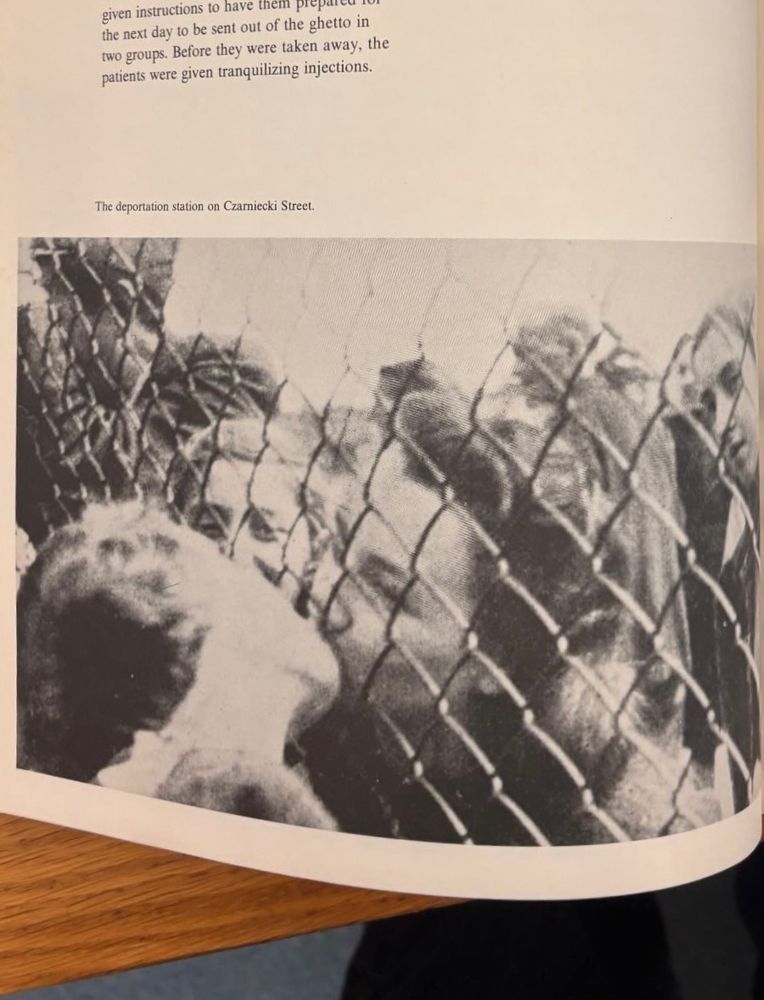 Two women kissing through a fence with staring intrusive onlookers 