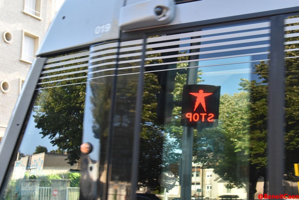 reflet d'un feu de signalisation piéton "Stop" dans les vitres du tramway