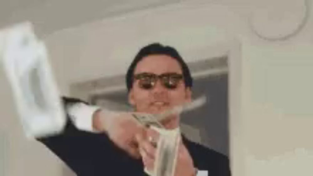 a man wearing sunglasses is holding a bunch of money in his hand .