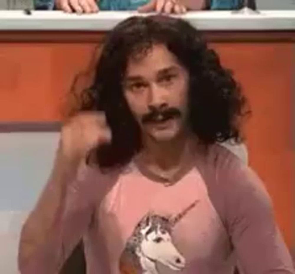 a man with long hair and a mustache wearing a pink shirt with a unicorn on it .