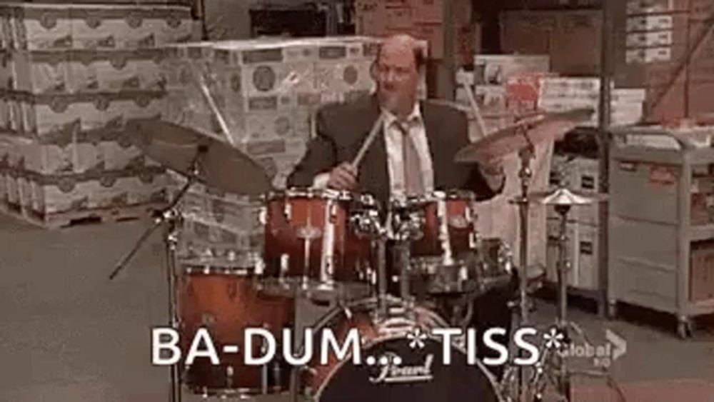 a man in a suit and tie is playing drums .