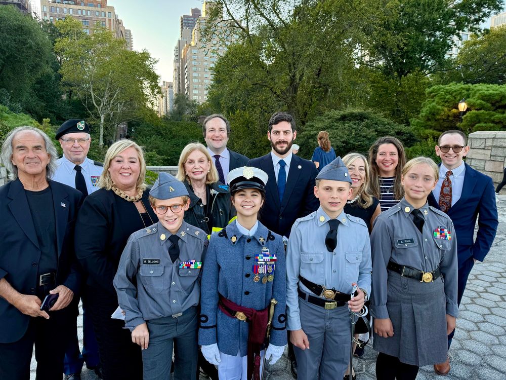 A group of Upper East Side community members and elected officials stand together smiling for a photo at the 9/11 memorial event