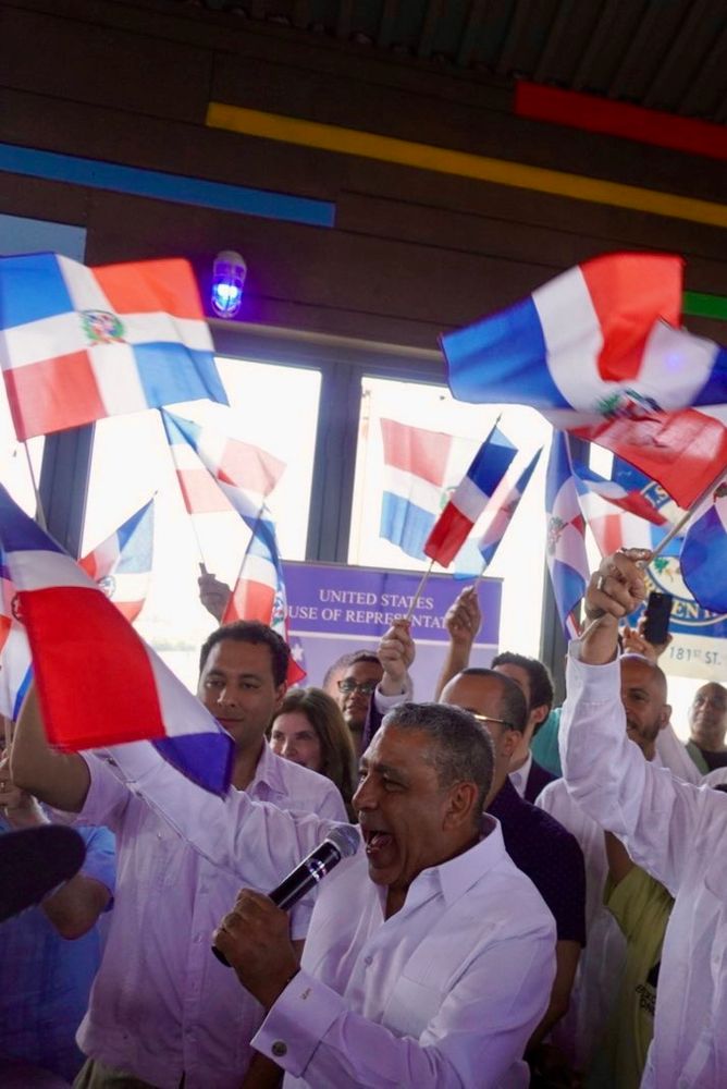 Congressman Espaillat speaking with Dominican flags being flown around in crowd