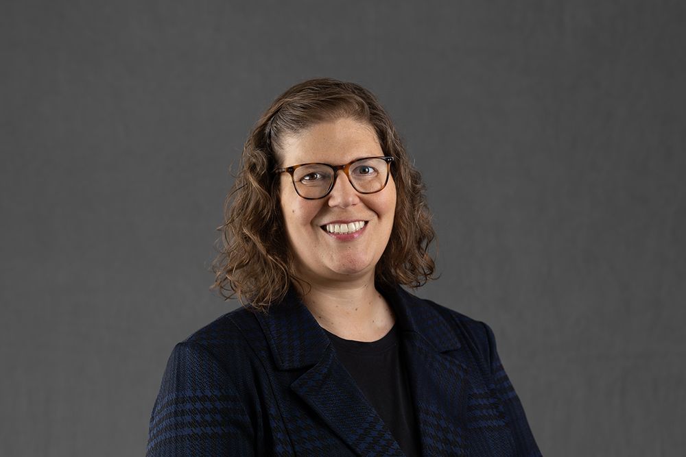 Carleton University Professor Laura Horak, with brown curly hair and glasses, smiling at the camera.