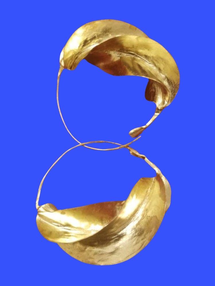 Against a royal blue background, gold-colored Fulani hoop earrings are interlaced