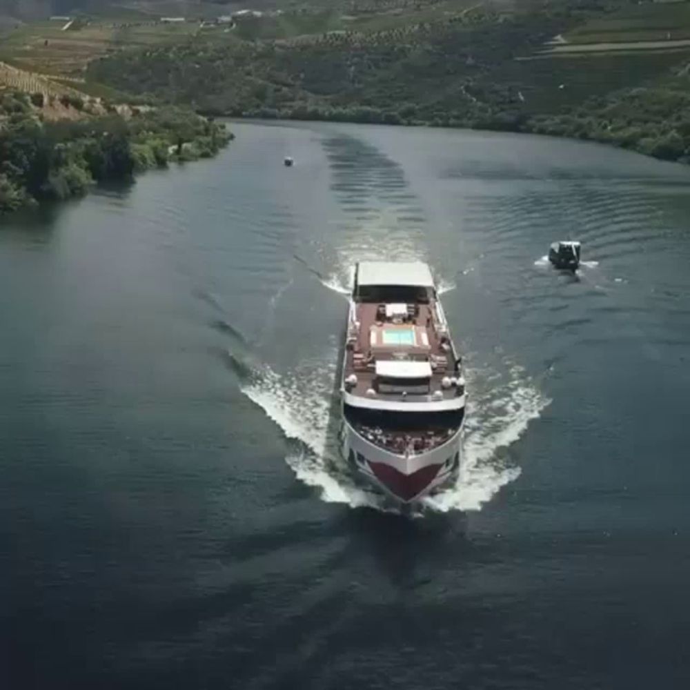 a large boat is floating on a river with a smaller boat in the background