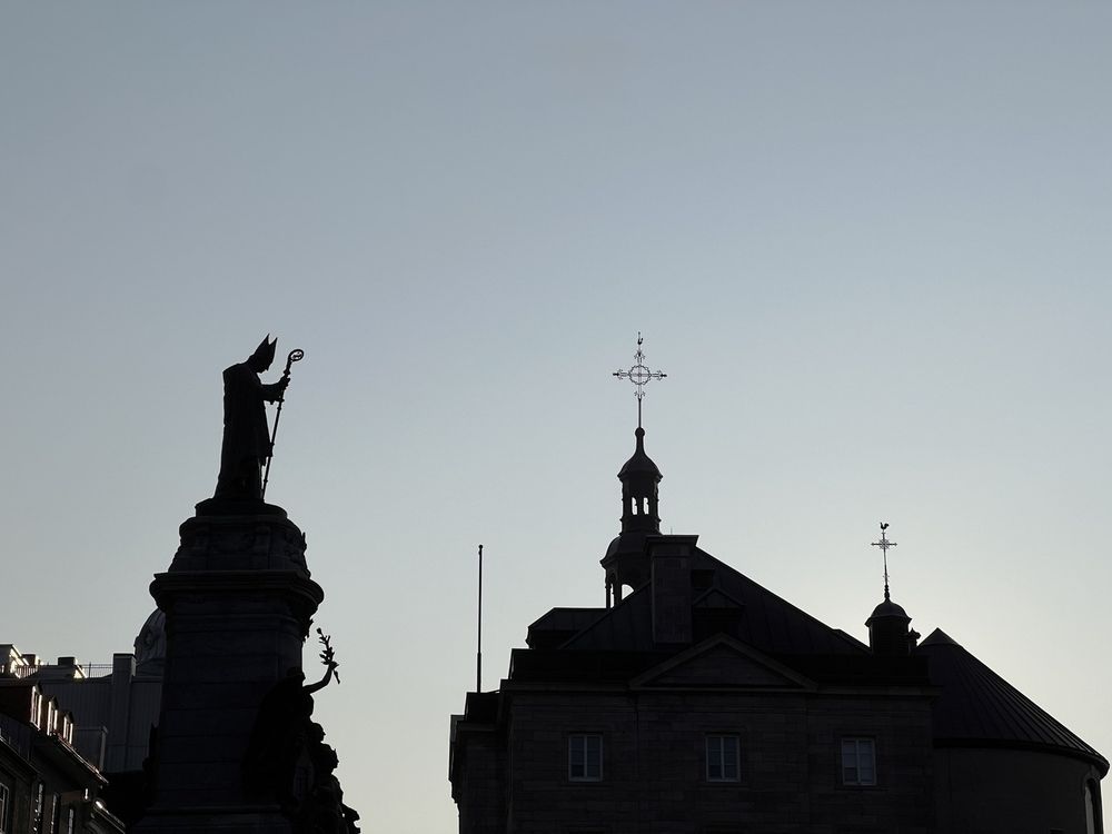 Saint François de Laval Monument with the steeple crosses of Notre-Dame de Québec Basilica-Cathedral all in silhouette