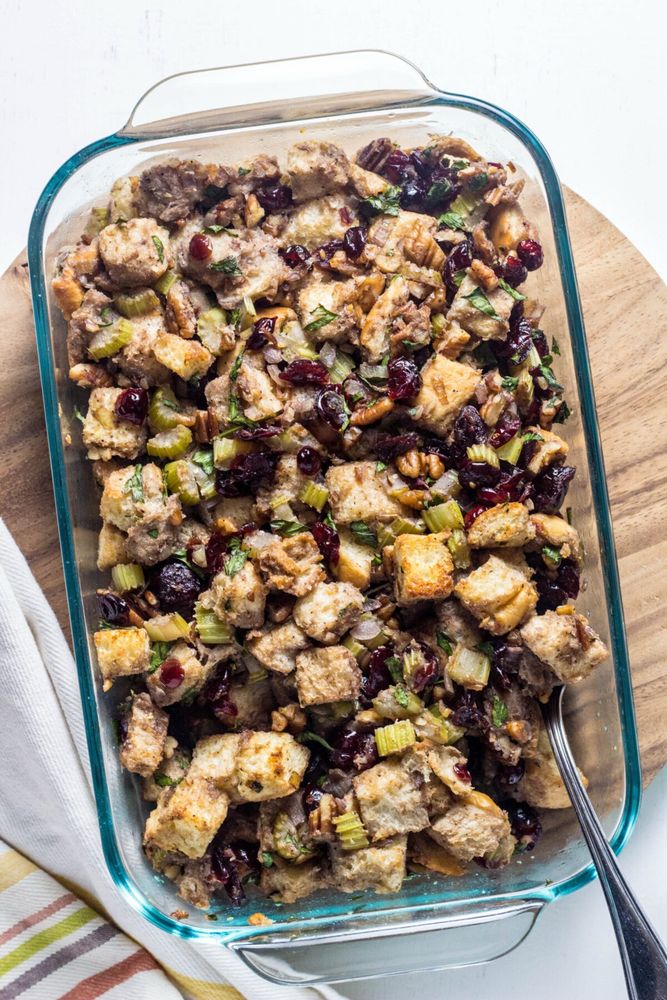 Overhead view of a baking dish with cranberry pecan stuffing. There is a serving spoon resting in the side of the dish. 