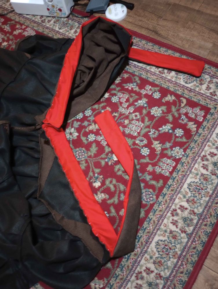 Both belts are pinned to the skirt. The sewing machine and pins are barely visible in the corner.