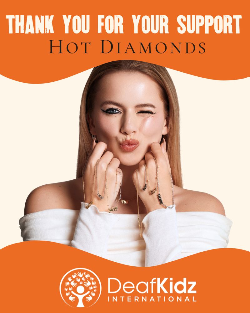 Tasha Ghouri, wearing a white off-shoulder top, smiles and winks while holding up several delicate gold necklaces with charms with words: forever, lucky, happy, mum, love and hope. The background is cream with bold orange waves at the top and bottom. Text at the top reads 'Thank you for your support, Hot Diamonds.' At the bottom is the DeafKidz International logo in white on an orange background.