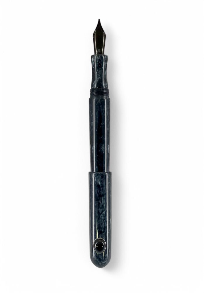 A GW GemPen 25 fountain pen on a white background, cap posted. The resin is black with light holographic glitter, a bluish white undertone, and a black nib. An onyx set in fine silver is attached to the cap as a rollstop.