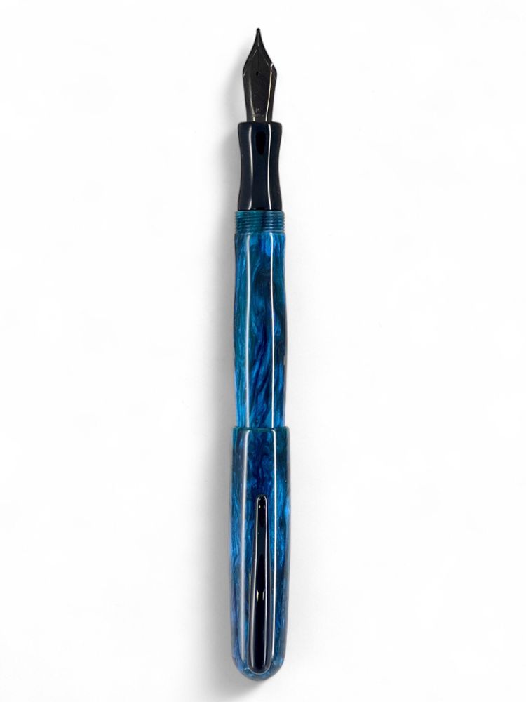 A teal and black fountain pen with black clip and nib and black ebonite section is shown with the cap posted against a white background
