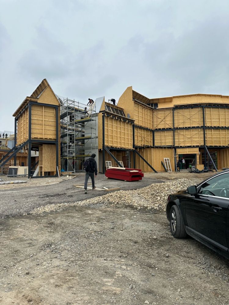 Photo taken on the outside of the backlot, showing the supports of the façade, as crew members work on scaffolding at the top.