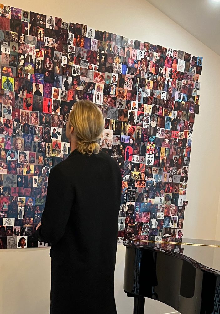 Sam Reid looks at the top right section of the fan art wall in the Writer’s Room Office by a grand piano.