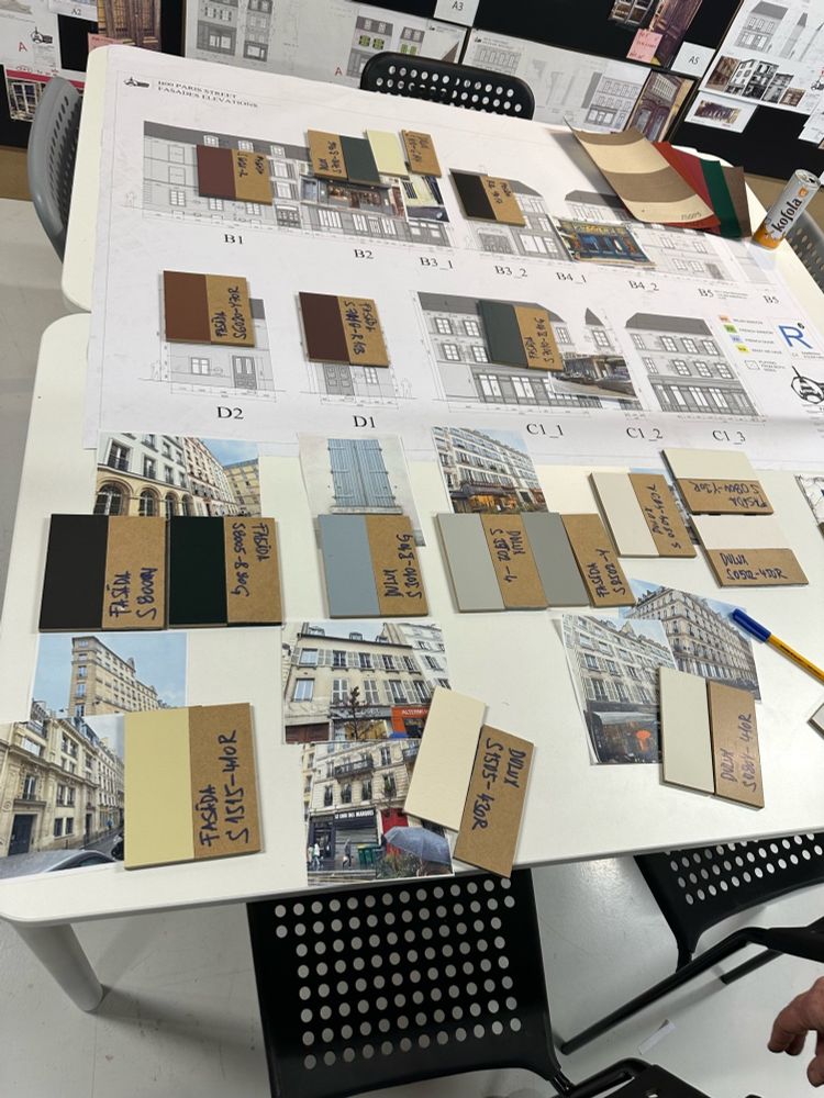 A white board with reference photos and paint colors for each building on the Parisian Street backlot. 