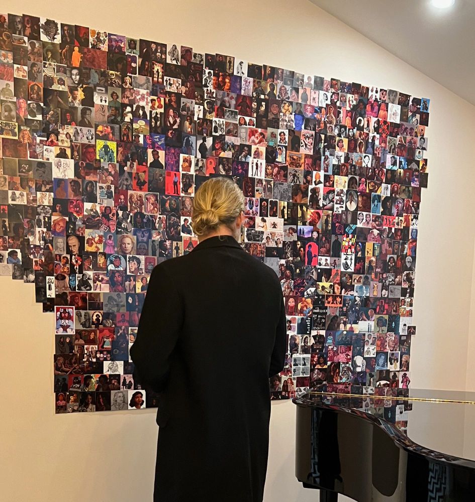 Sam Reid looks at the bottom right section of the fan art wall in the Writer’s Room Office by a grand piano.