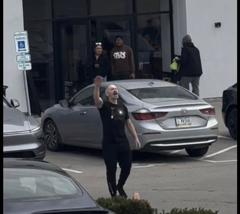 Unnamed white man in black tshirt and pants gives nazi salute to protesters at Kansas City Tesla dealership