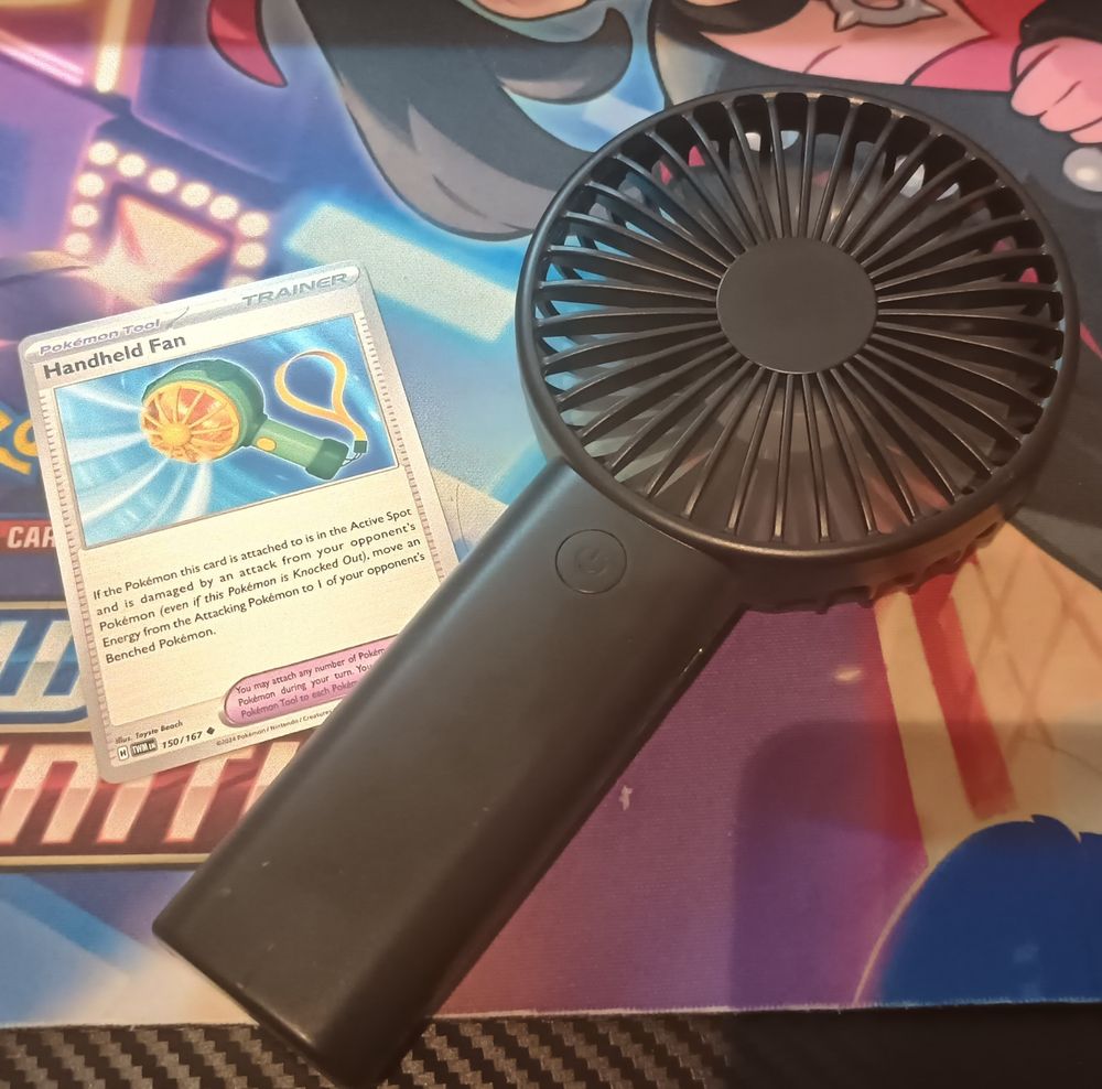 A Handheld Fan card from the Pokémon TCG next to a real handheld electronic fan