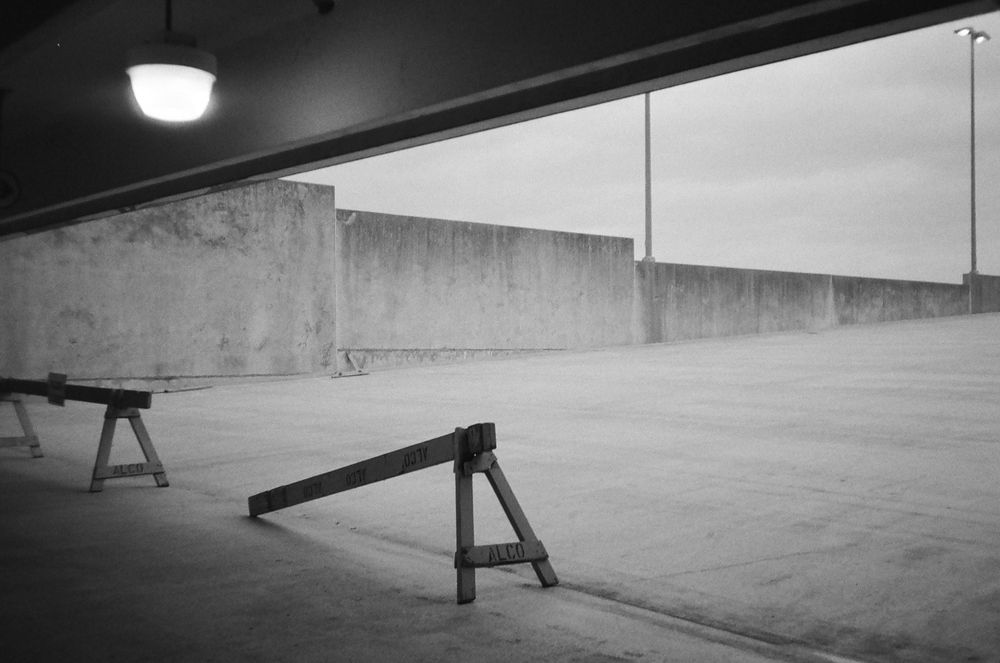 A black and white photo of sawhorses on the top of a parking garage.