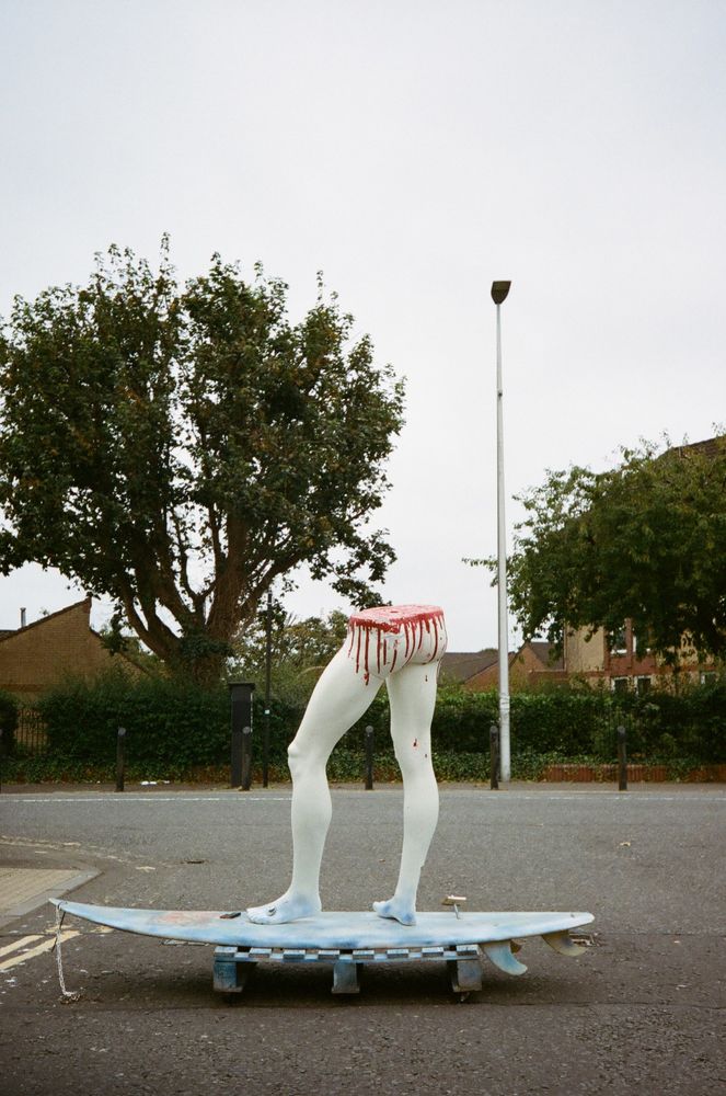 Street art of the bottom half of a mannequin on a surf board.