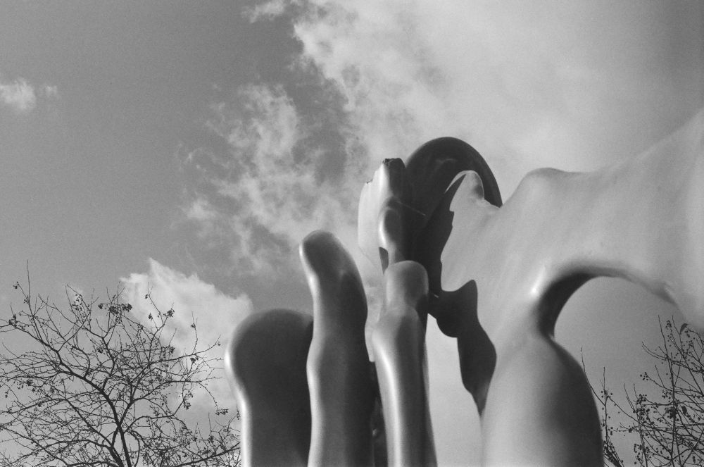 A black and white photo of an art installation stretching toward a cloudy sky.