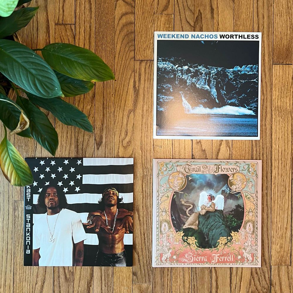 A top down photo of three records on a hard wood floor. Those three records are
Weekend Nachos’ Worthless, Sierra Ferrell’s Trail of Flowers, and OutKast’s Stankonia. 