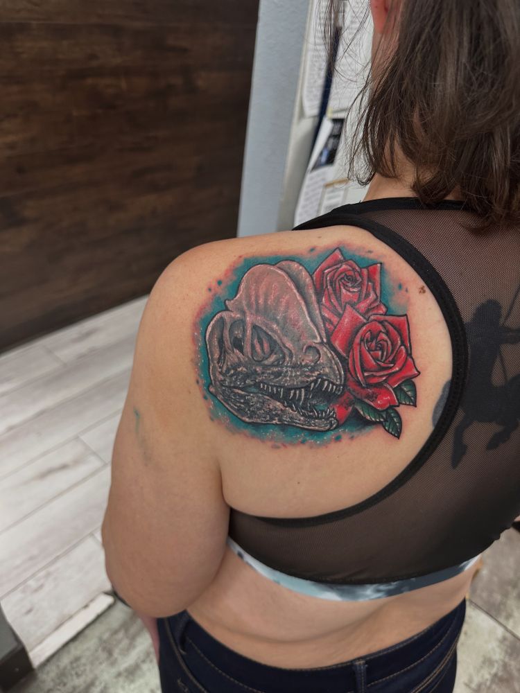 tattoo of a dilophosaurus skull and flowers