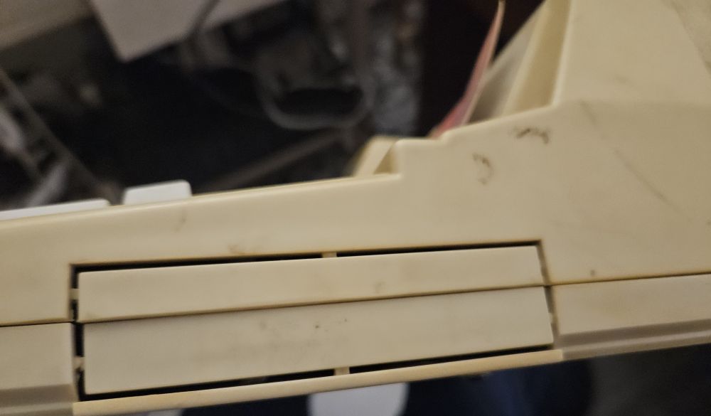 Photo of the side of the console, showing a sort of rectangular gate being held in place by plastic tabs. It can't be opened without breaking the tabs.
