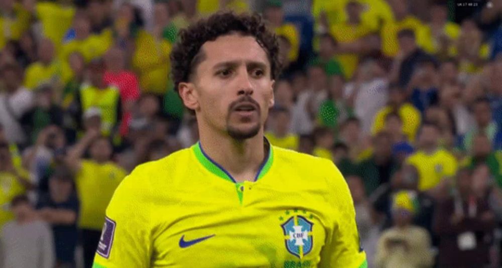 a soccer player wearing a yellow jersey with the brazilian flag on it is standing in front of a crowd .